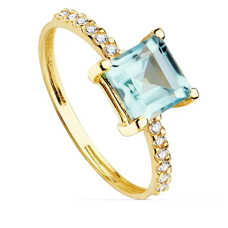 Sortija oro 18k centro piedra imitación topacio azul 6x6mm. cuerpo detalle circonitas